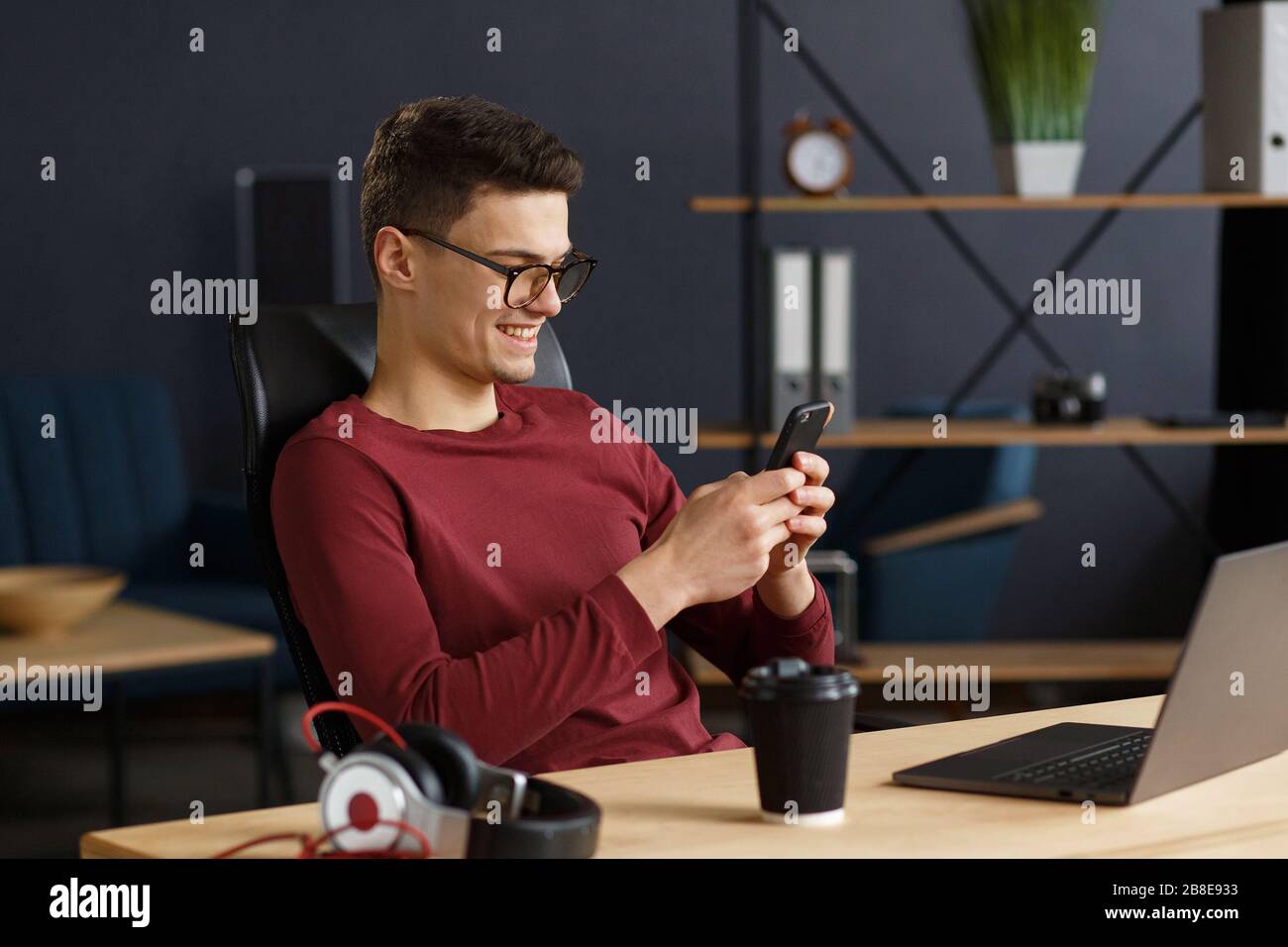 Young man using smartphone and smiling. Happy businessman using Stock Photo