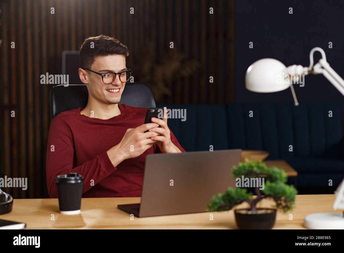 Young man using smartphone and smiling. Happy businessman using Stock Photo