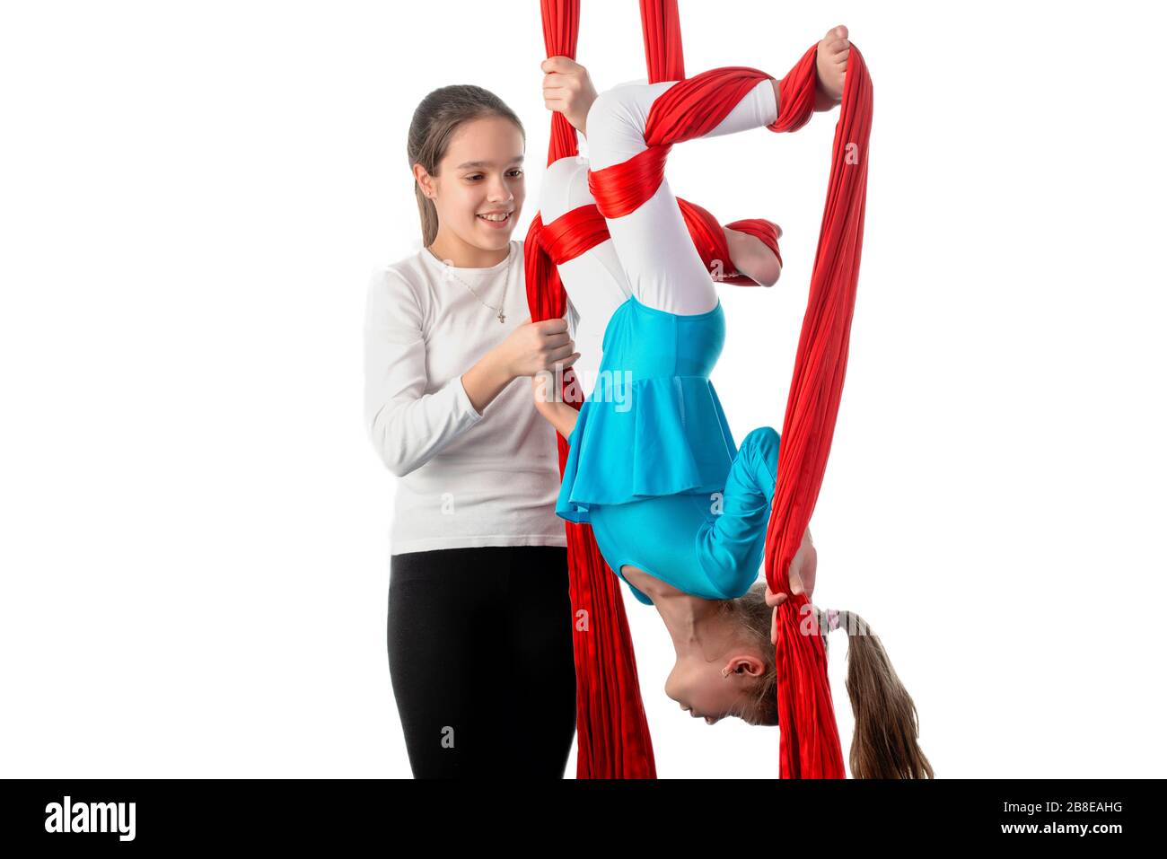 Teenage girl helps her little sister to properly fix herself on red air ...