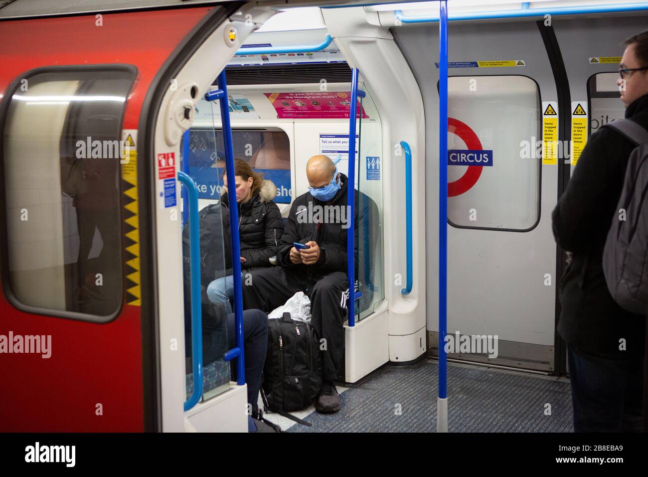 Commuters with face masks on the London Underground during coronavirus lockdown, March 2020 Stock Photo