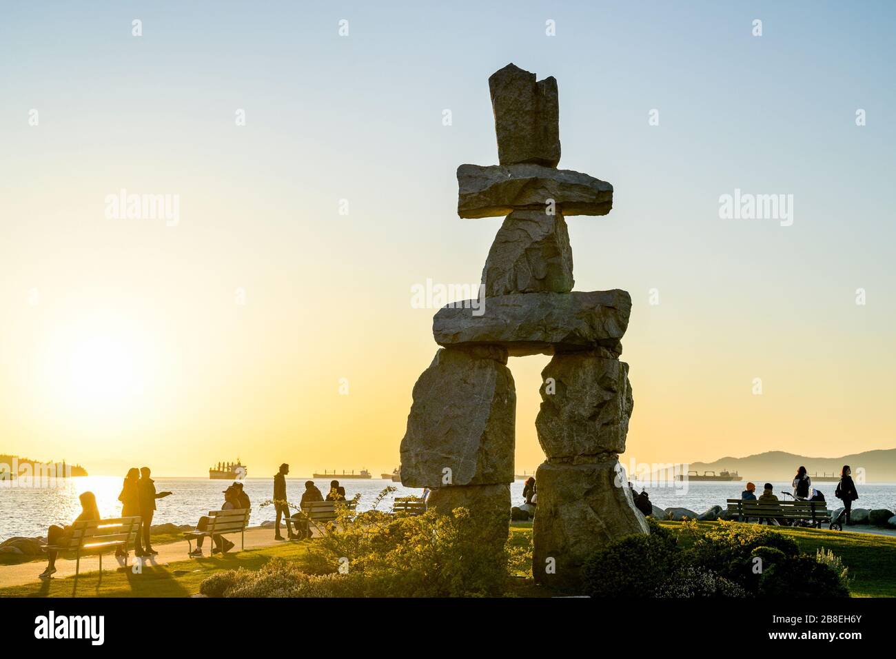 People disregard social distancing order and congregate at Inukshuk at sunset, English Bay, Vancouver, British Columbia, Canada Stock Photo