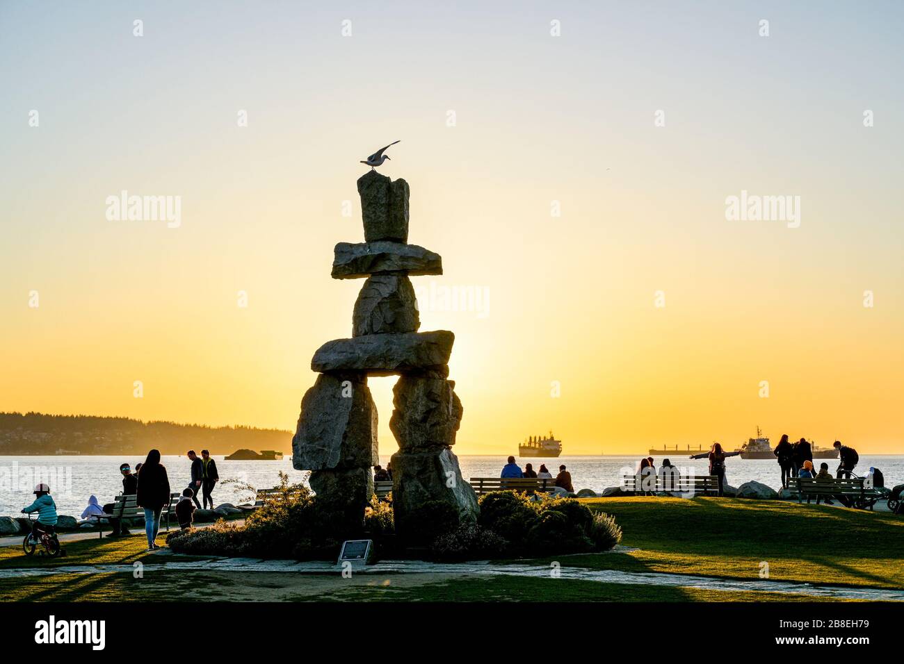 People disregard social distancing order and congregate at Inukshuk at sunset, English Bay, Vancouver, British Columbia, Canada Stock Photo