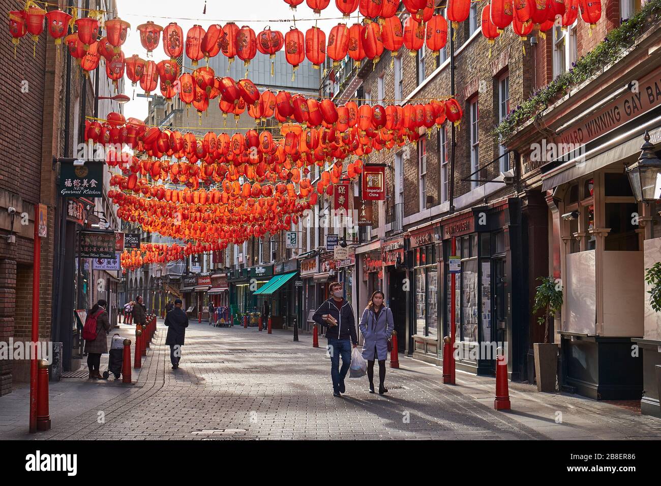 March 21st, 2020-Soho, London, England: Two people wear face masks in a deserted Chinatown during the Coronavirus pandemic Stock Photo