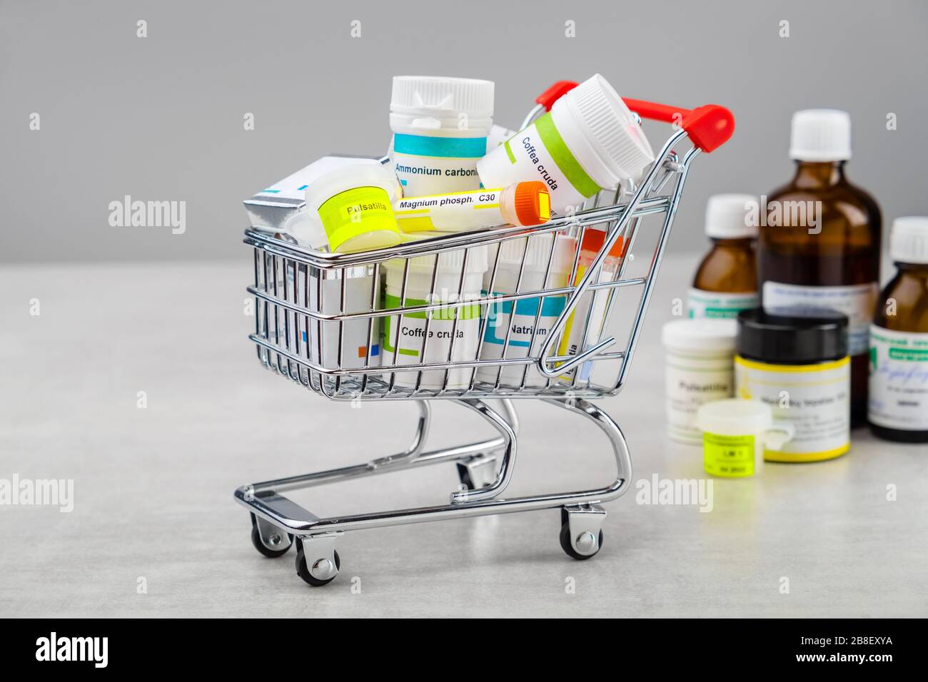 Mini shopping cart full of homeopathic remedies with typical international names: pulsatilla, ammonium carbonicum, magnium phosphopicum, coffea cruda, Stock Photo