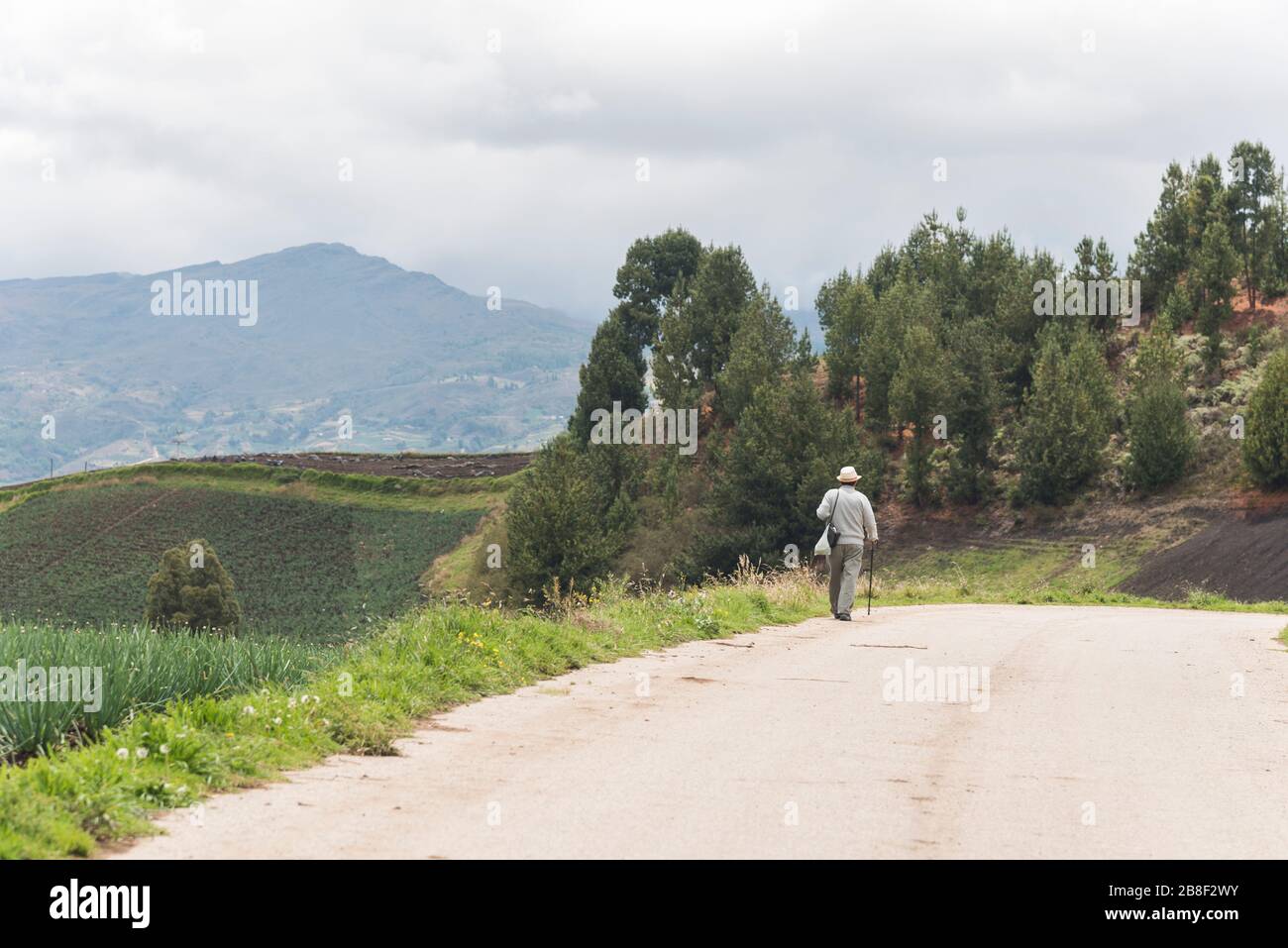 Aquitania, Boyaca / Colombia; April 8, 2018: man walking on a country road, in the middle of a green mountainous landscape, a cloudy day Stock Photo