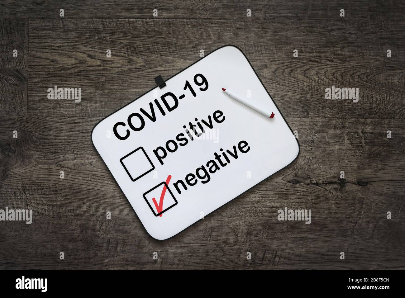 White board with negative test results for COVID-19 virus on a dark wooden background. Stock Photo