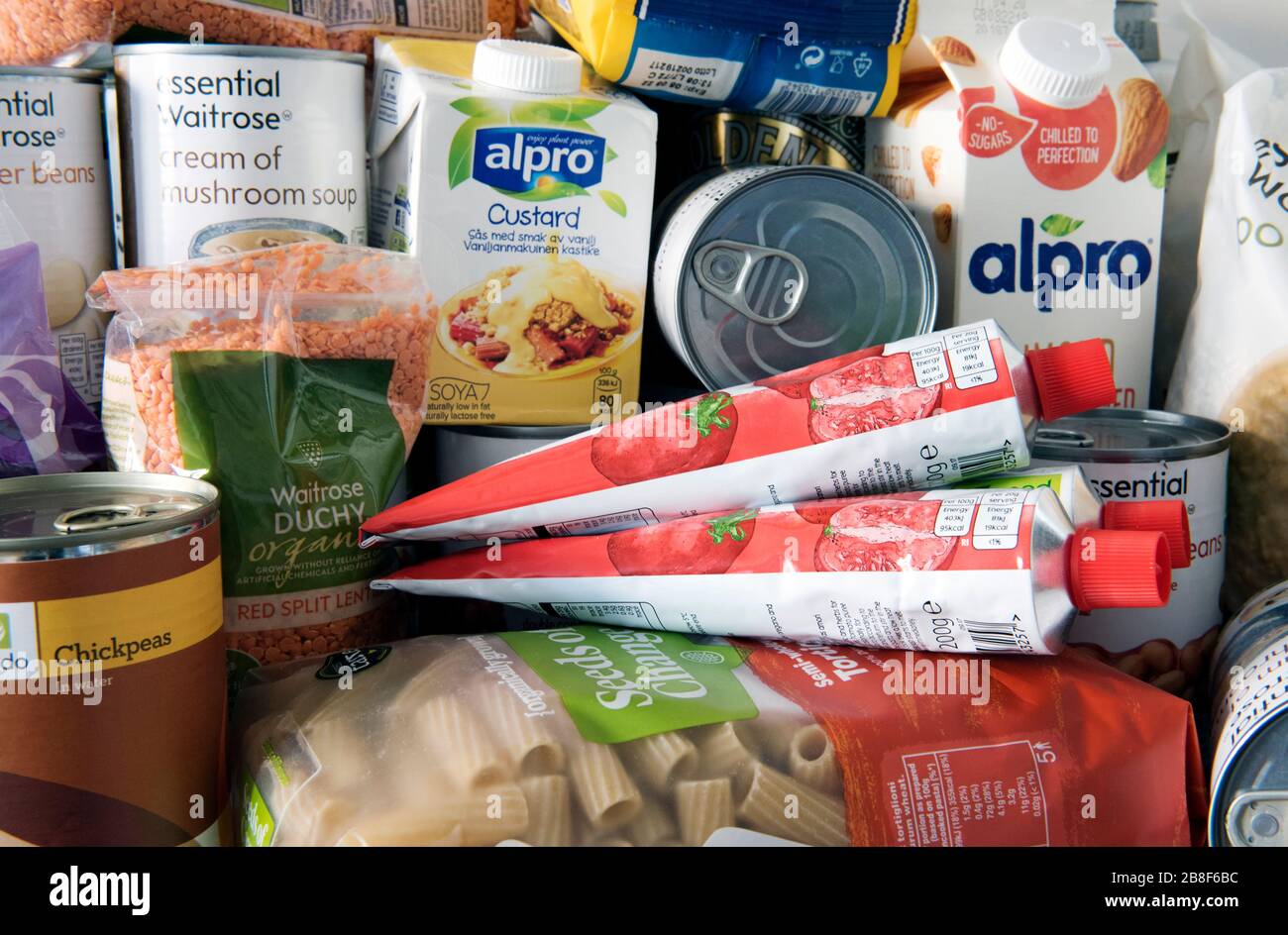 Stockpiled tins and packets of dried food piled up on kitchen work surface after home delivery.  Stockpiling due to Coronavirus pandemic. UK Stock Photo