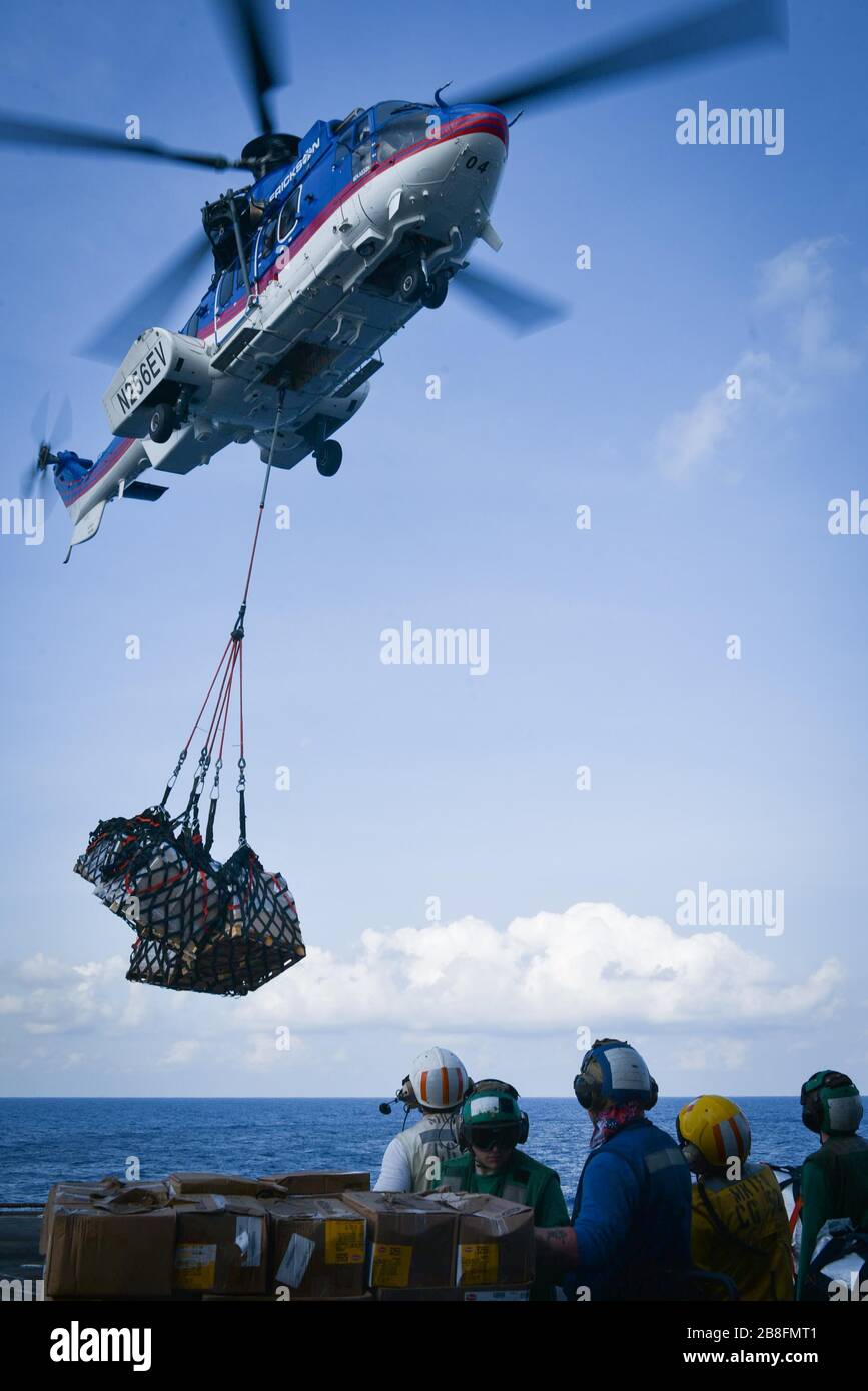 SOUTH CHINA SEA (March 14, 2020) U.S. Sailors collect cargo aboard the Ticonderoga-class guided-missile cruiser USS Bunker Hill (CG 52) from a Eurocopter AS332 Super Puma, assigned to the dry cargo and ammunition ship USNS Carl Brashear (T-AKE 7) during a replenishment-at-sea March 14, 2020. Bunker Hill, part of the Theodore Roosevelt Carrier Strike Group, is on a scheduled deployment to the Indo-Pacific. (U.S. Navy photo by Mass Communication Specialist 3rd Class Nicholas V. Huynh) Stock Photo