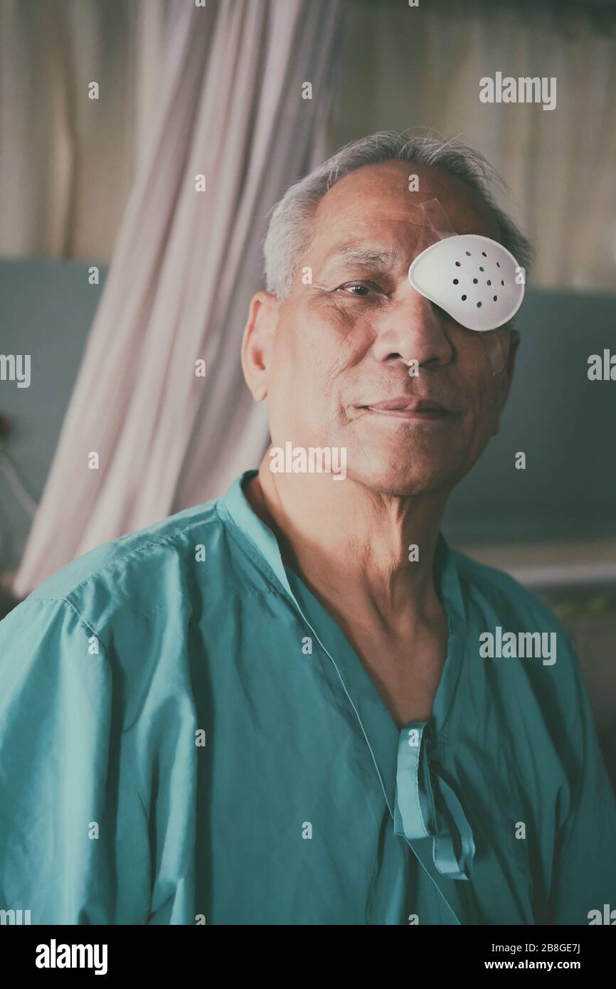 patient covering eye with protective shield & medical plaster after