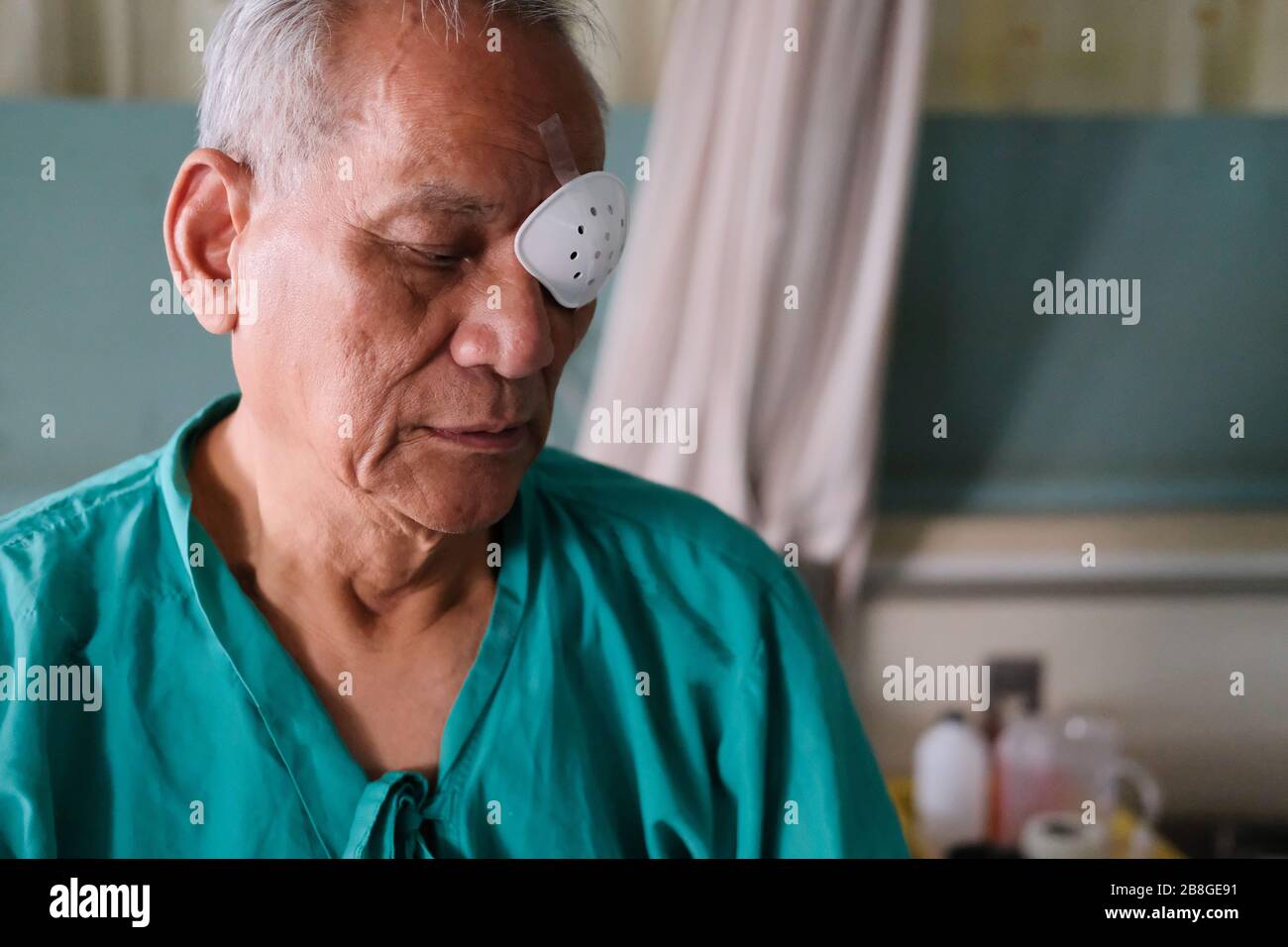 patient covering eye with protective shield & medical plaster after