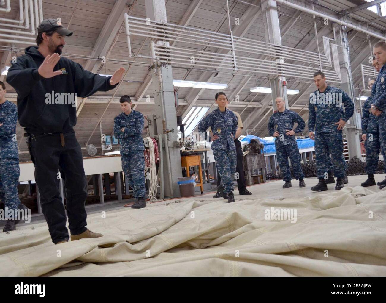 A rigging leader with Naval History and Heritage Command, teaches U.S. Sailors assigned to USS Constitution to fold the spanker sail in Charlestown, Mass., Feb. 29, 2012 120229 Stock Photo