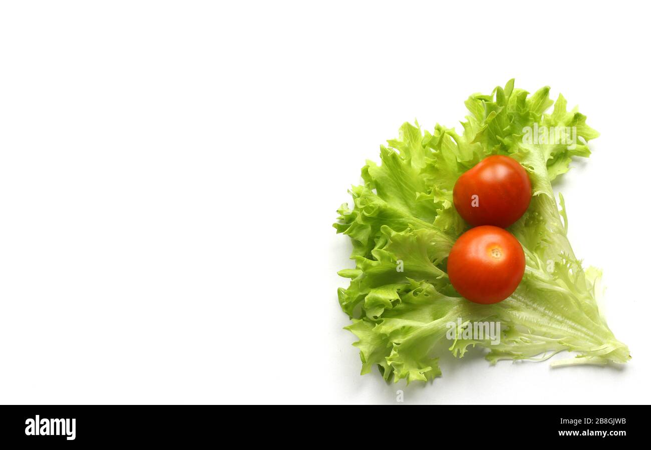 Red cherry tomatoes and lettuce leaves on white background Stock Photo