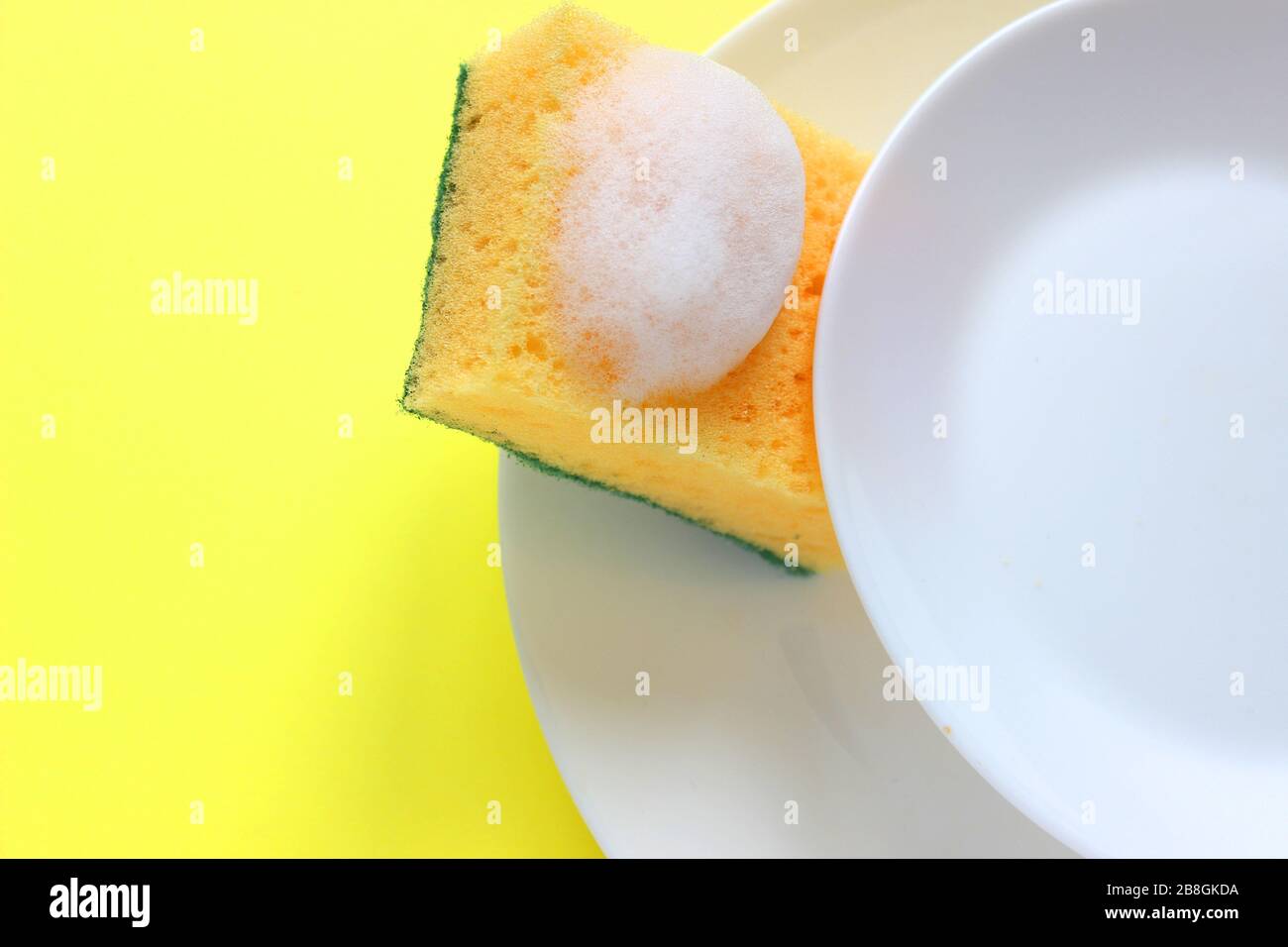 means for washing dishes and sponges on a plate on a colored background. household chores, washing dishes Stock Photo