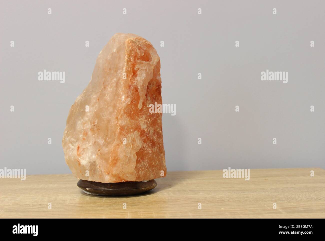 Turned off a Himalayan pink salt lamp carved in the shape of a rock on a light table. Stock Photo