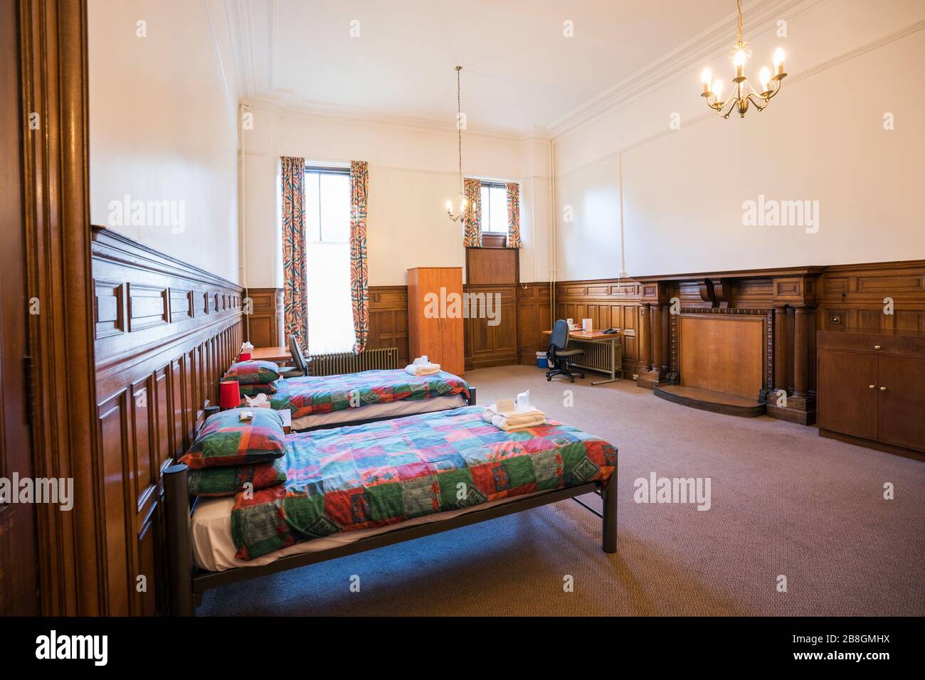 Interior of a female dorm room with chandeliers, tall ceilings, wooden panelsing and twin beds that is open to  public housing in summer months, St. A Stock Photo