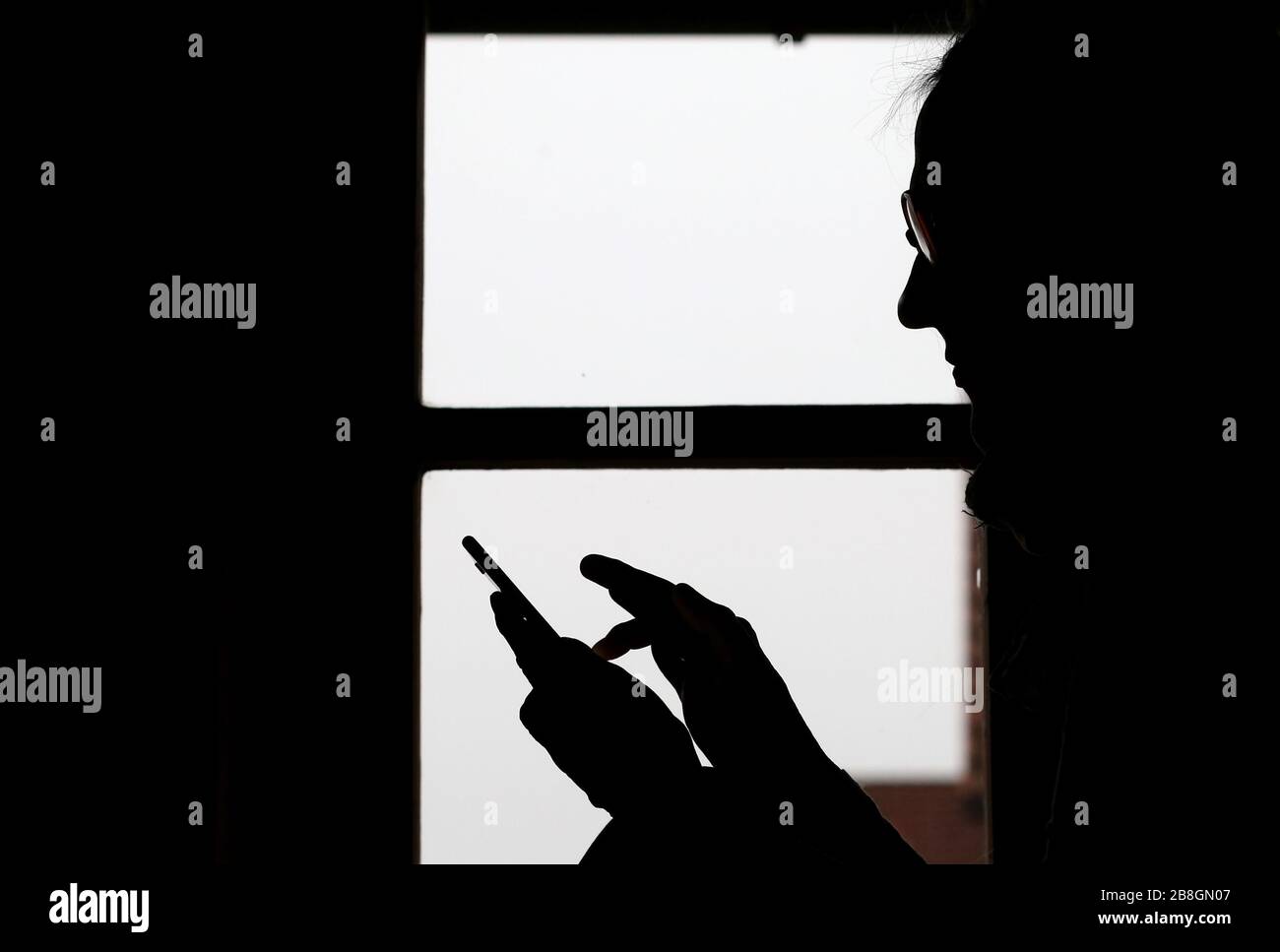 Kaufbeuren, Germany. 21st Mar, 2020. Illustration! A woman taps on the display of a smartphone in front of a window in her house (to dpa-KORR: 'Storage frenzy or a chance? How to (survive) in isolation' from 22.03.2020). Credit: Karl-Josef Hildenbrand/dpa/Alamy Live News Stock Photo