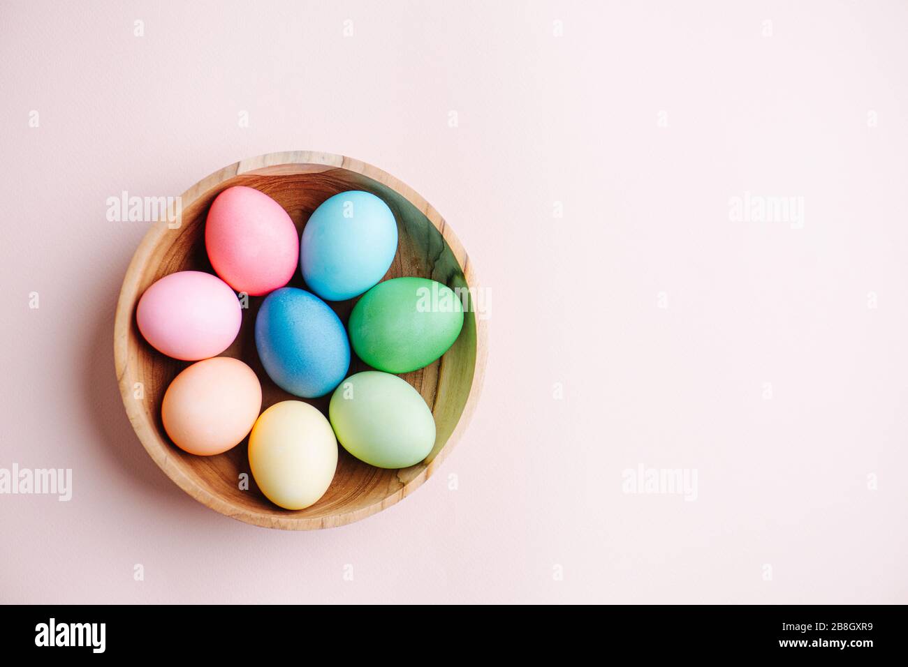 Painted multi-colored easter eggs in a wooden bowl. Top view. Stock Photo