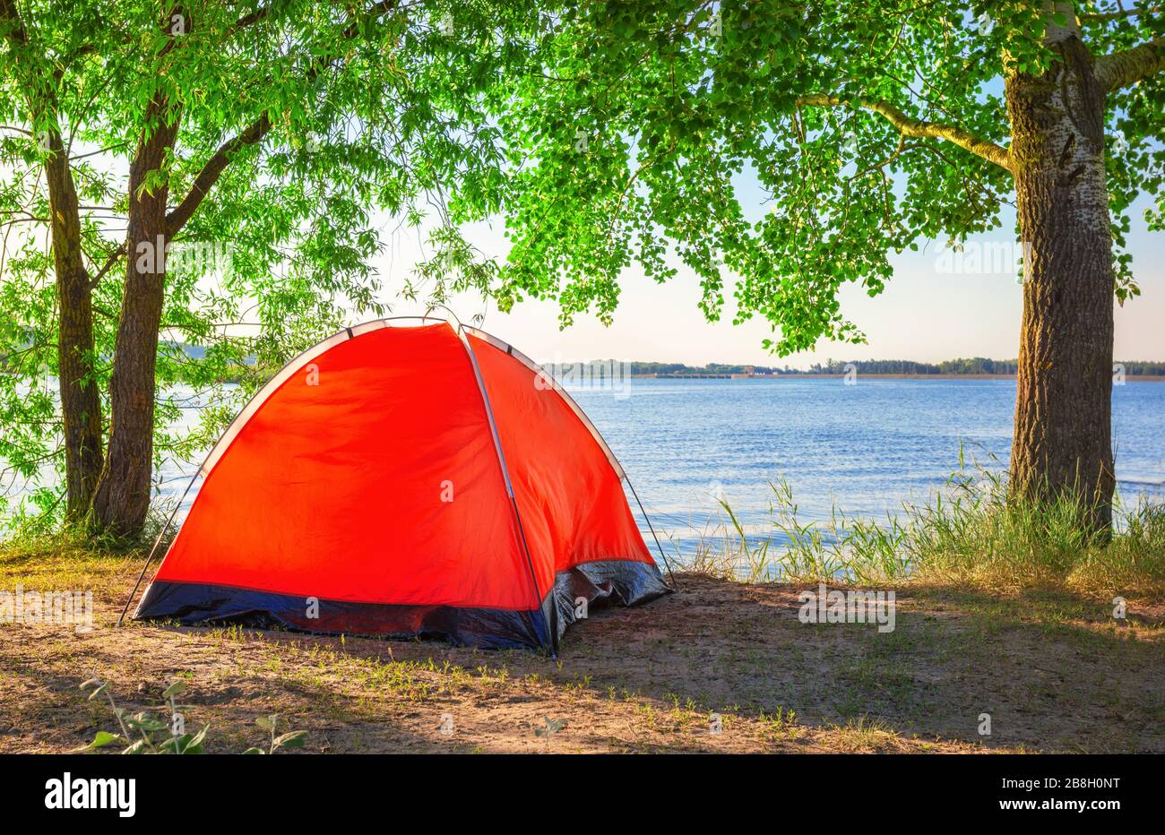 Red tourist tent on lake in summer Stock Photo