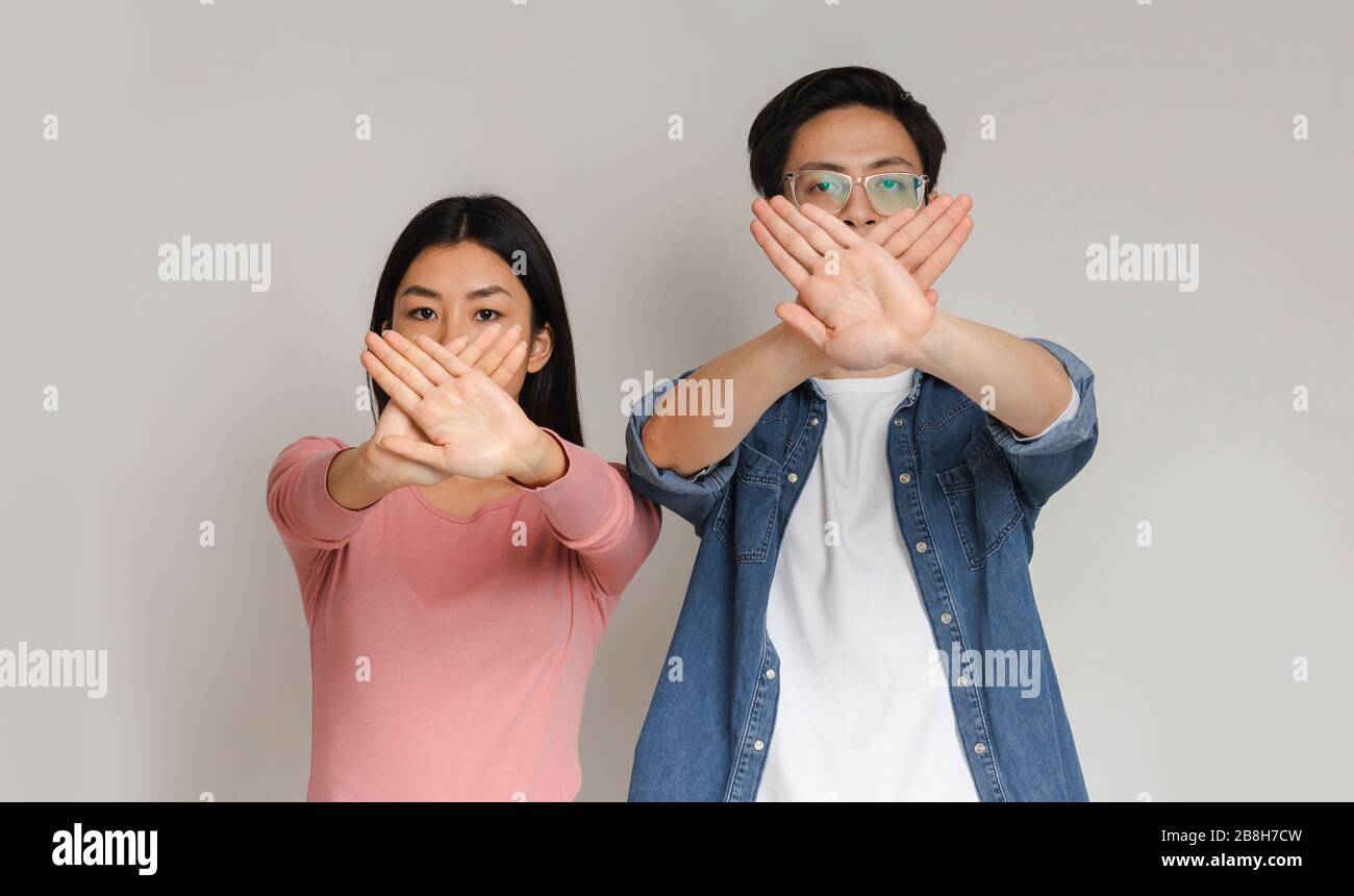 Young asian couple holding crossed palms against mouths Stock Photo