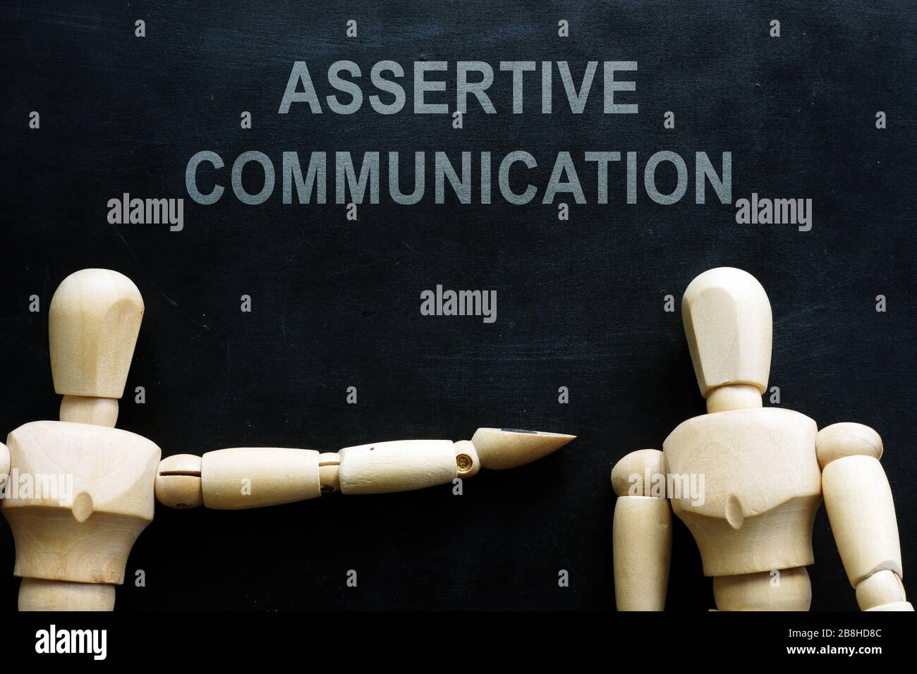 Assertive communication phrase and two wooden figures. Stock Photo