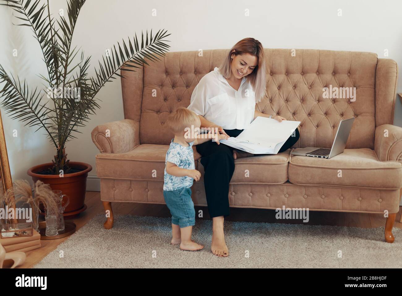 Beautiful business woman working at home. Multi-tasking, freelance and motherhood concept. Working mother career Stock Photo