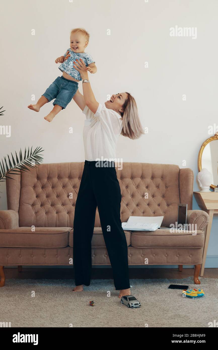 Young mother with her child working at home. Business mom takes a break. Multi-tasking, freelance and motherhood concept Stock Photo