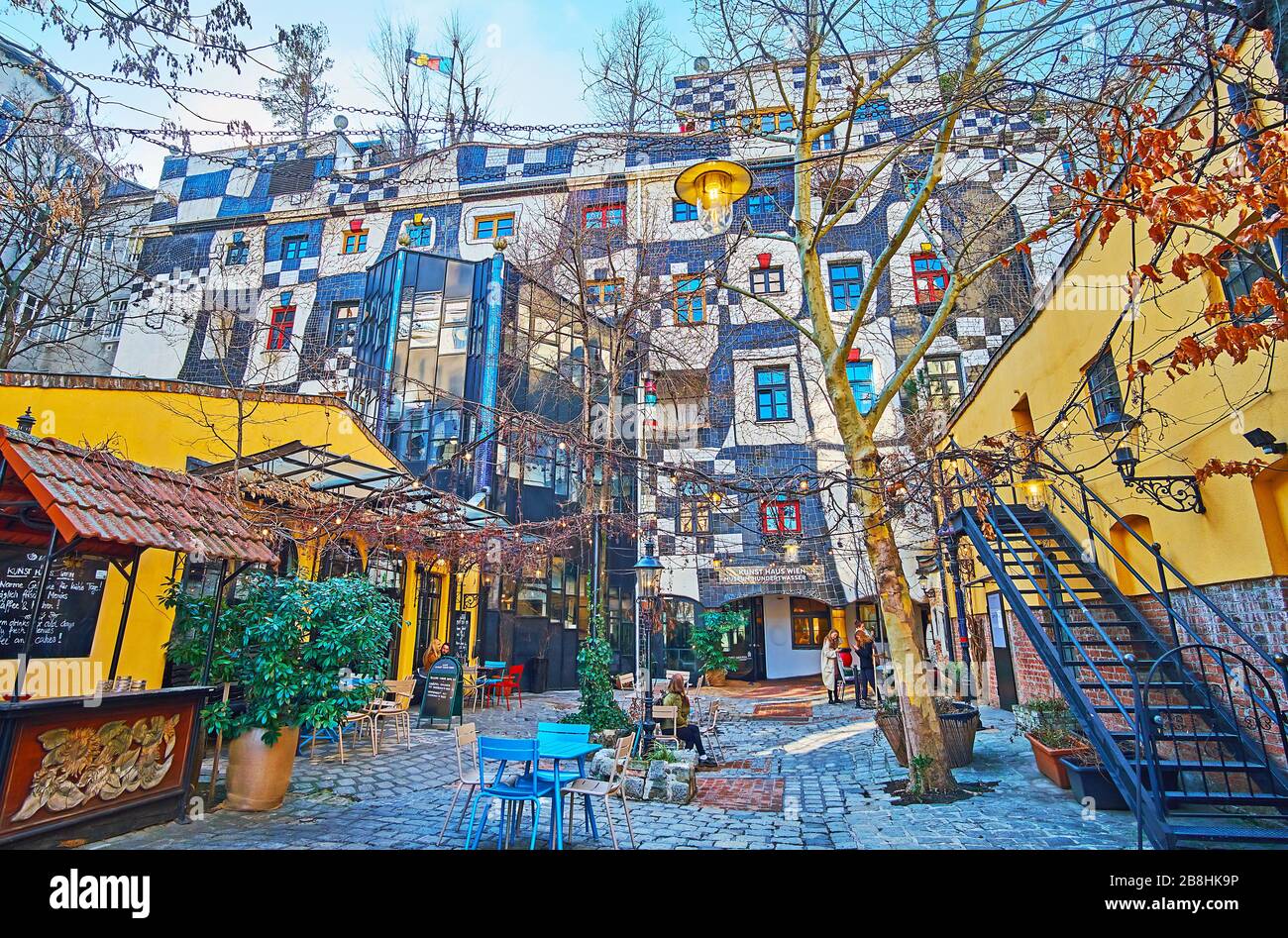 VIENNA, AUSTRIA - FEBRUARY 19, 2019: The courtyard of Kunst Haus Wien with tables of outdoor cafe and unusual wall of the Hundertwasser museum, on Feb Stock Photo