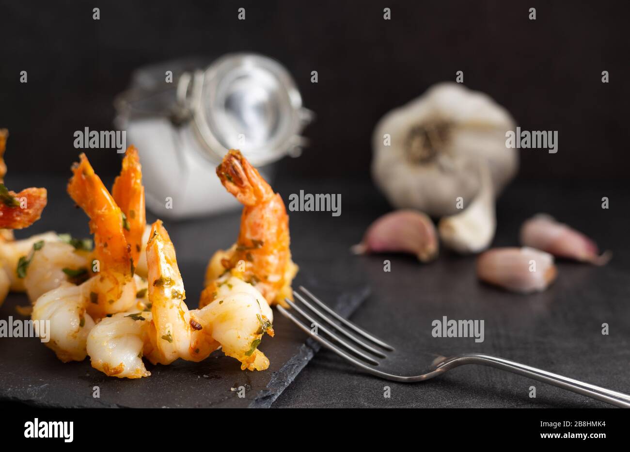 Delicious seafood. Homemade prawns with garlic sauce on a black plate. Stock Photo