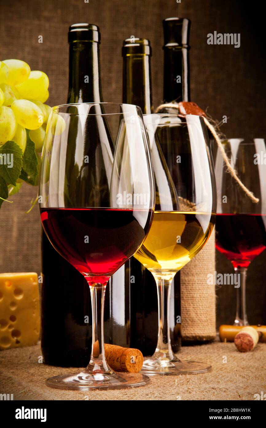 Still life with wine bottles, glasses, grapes and cheese Stock Photo - Alamy