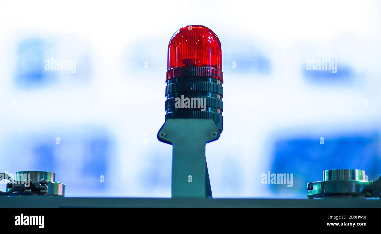 The signal lamp. Industrial red signal lamp on a red background. The concept of security. Stock Photo