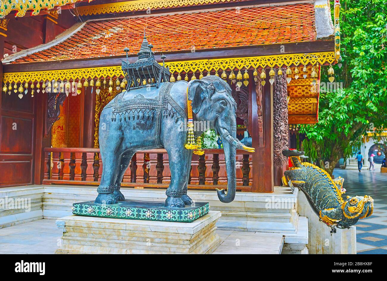 The bronze elephant statue at the side wall of Vihara (shrine), guarded by mom mythic creature, seen on background, Wat Phra That Doi Suthep temple, C Stock Photo