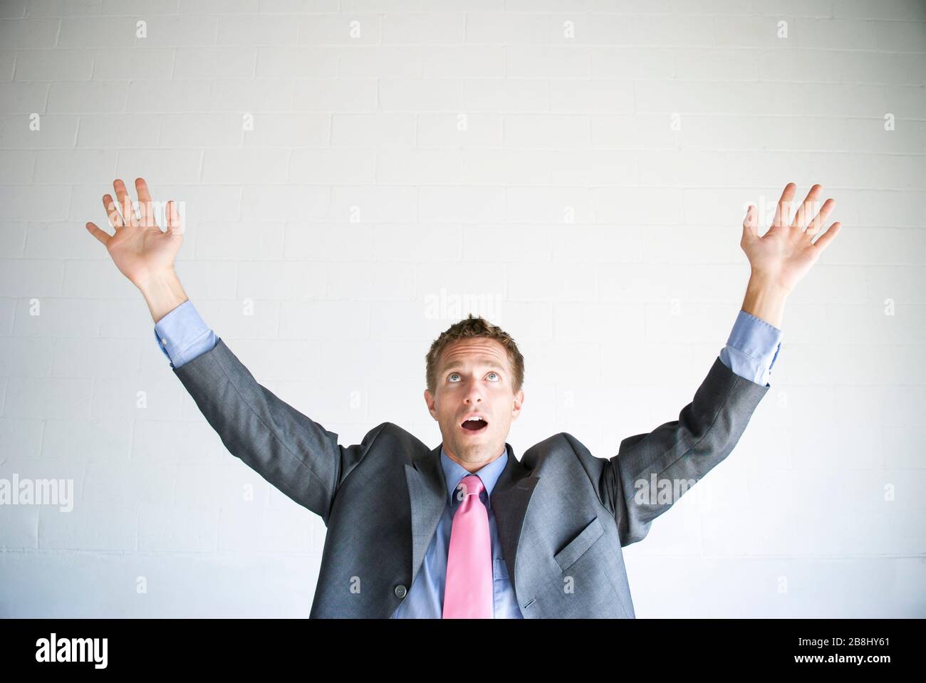 Businessman holding arms out looking up at copy space with an