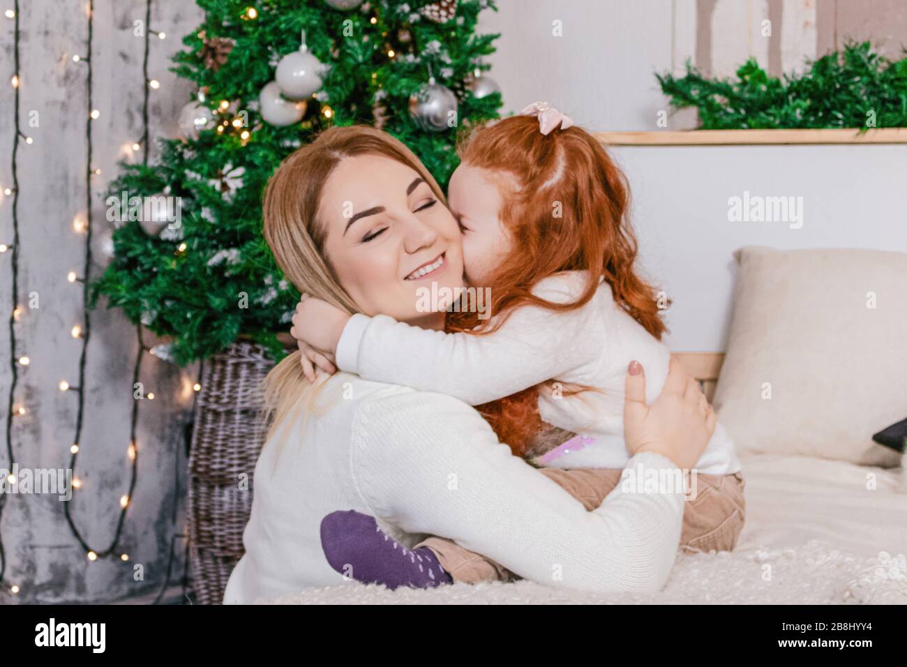 little girl kissing her mom at christmas photo Stock Photo