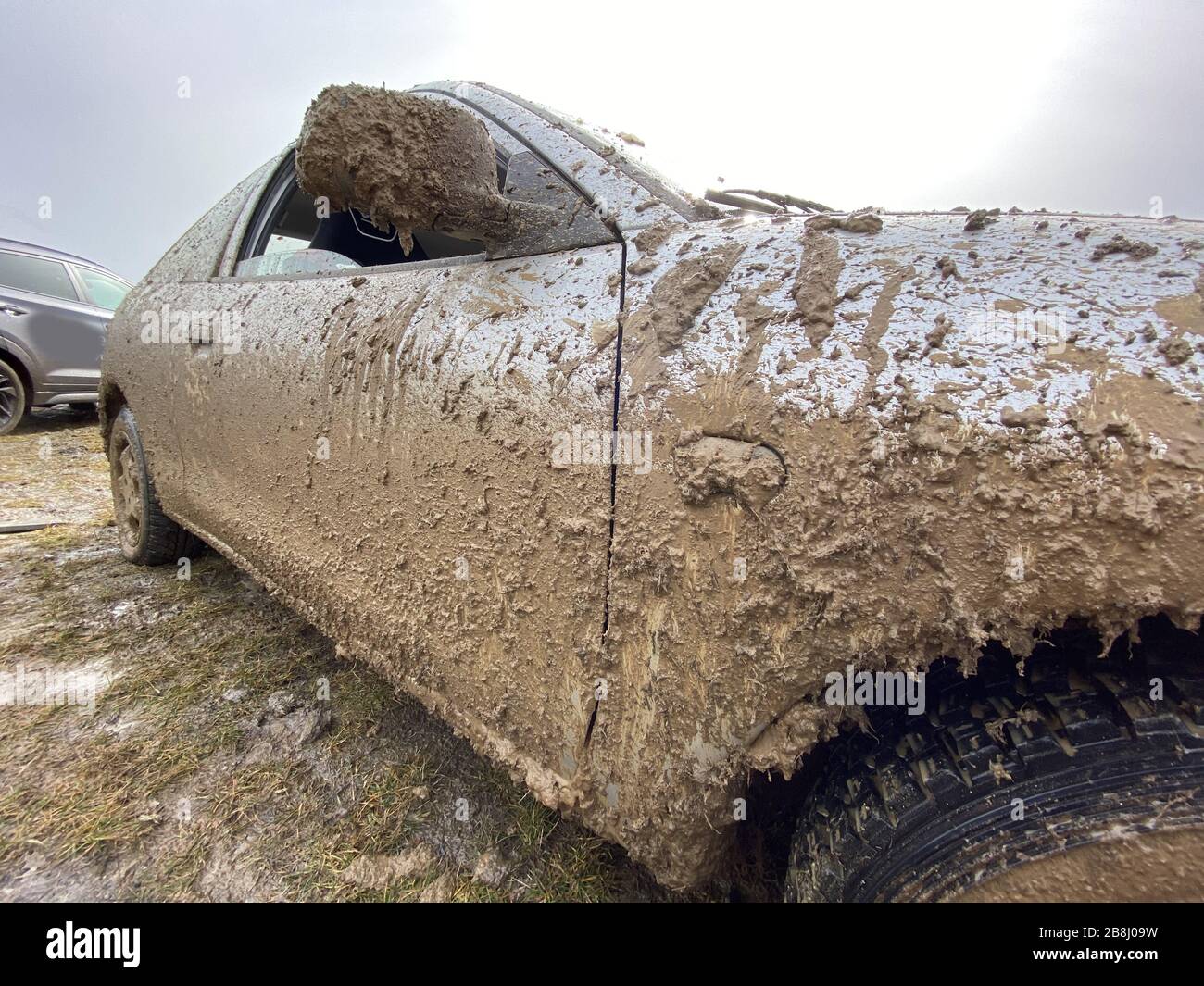 The detail of the car completely dirty by mud after the drag race on a field during winter. It needs complete cleaning of the exterior and interior. Stock Photo