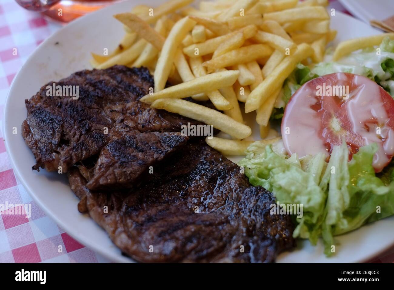 Steak and chips with salad at a tourist bistro in Paris near the Eiffel Tower. Stock Photo