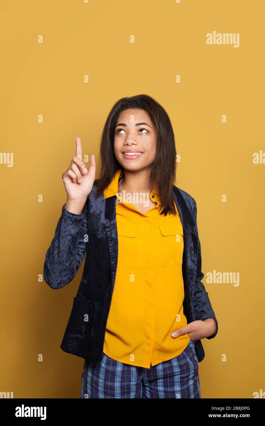 Black woman student pointing finger up on vivid yellow background Stock Photo