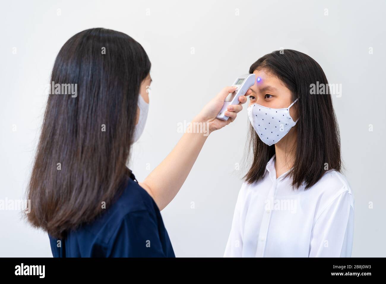 Young Asian woman wearing N95 mask, getting her temperature check health concept Stock Photo
