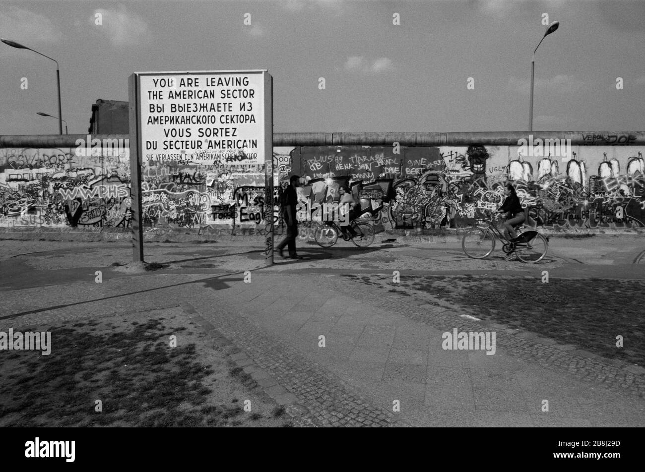 A sign indicating the end of the American sector next to the Berlin Wall at Potsdamer Platz, West Berlin. The Berlin Wall was a barrier constructed by the German Democratic Republic (GDR, East Germany) starting on 13 August 1961, that completely cut off West Berlin from surrounding East Germany and from East Berlin. The Wall was opened on 9. November 1989 allowing free movement of people from east to west. Stock Photo