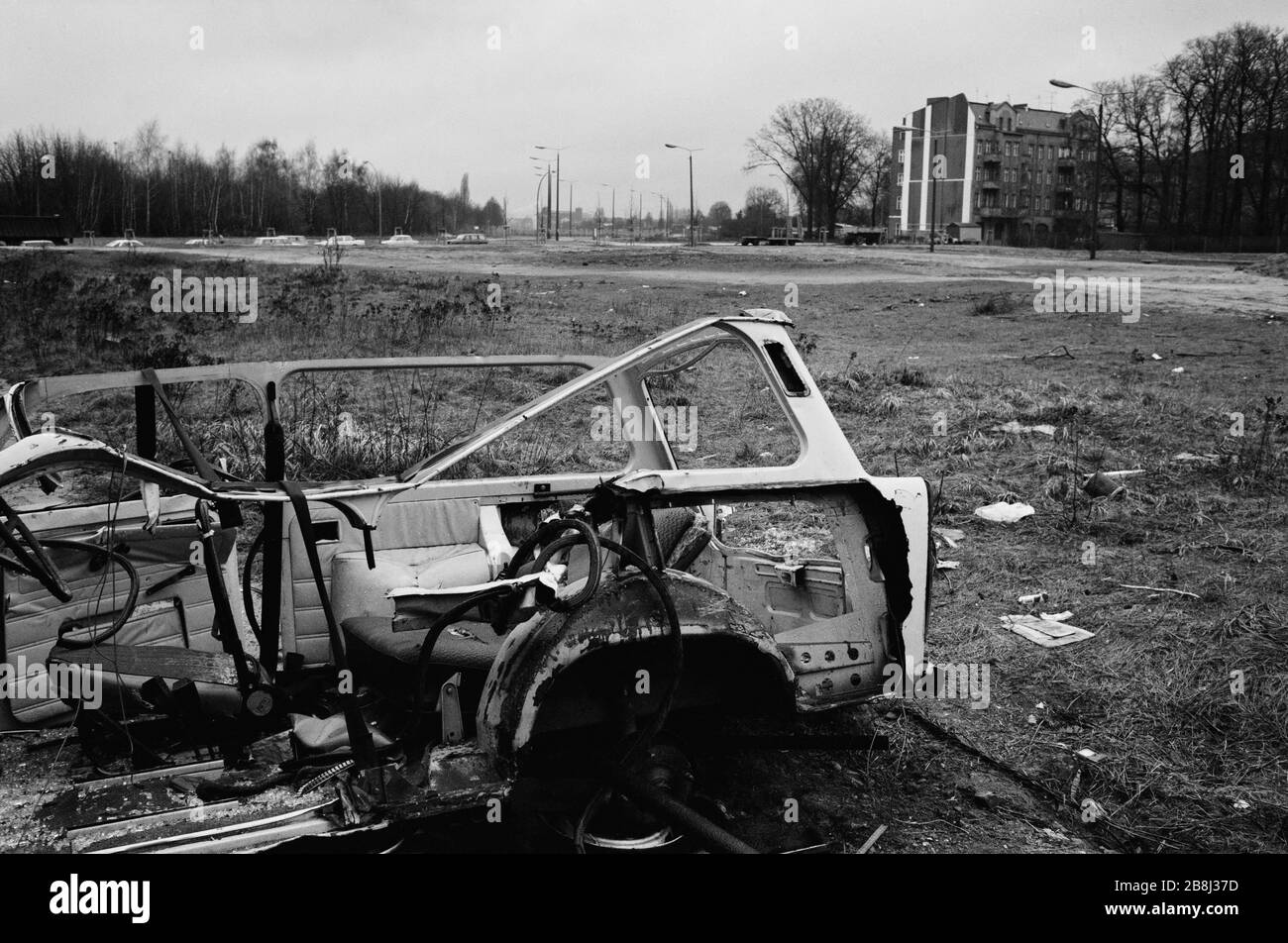 A wrecked shell of an East German Trabant motor car near a section of the course of the former Berlin Wall, Bornholmer Strasse, Berlin. The Berlin Wall was a barrier constructed by the German Democratic Republic (GDR, East Germany) starting on 13 August 1961, that completely cut off West Berlin from surrounding East Germany and from East Berlin. The Wall was opened on 9. November 1989 allowing free movement of people from east to west. Stock Photo