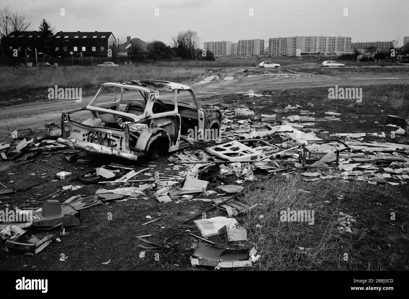 A wrecked shell of an East German Trabant motor car near a section of the course of the former Berlin Wall, Oranienburg, Berlin. The Berlin Wall was a barrier constructed by the German Democratic Republic (GDR, East Germany) starting on 13 August 1961, that completely cut off West Berlin from surrounding East Germany and from East Berlin. The Wall was opened on 9. November 1989 allowing free movement of people from east to west. Stock Photo