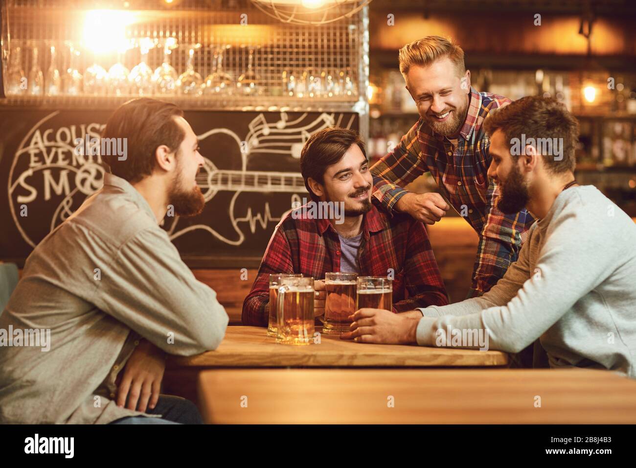 A group of friends is sitting in a bar with glasses of beer. Stock Photo