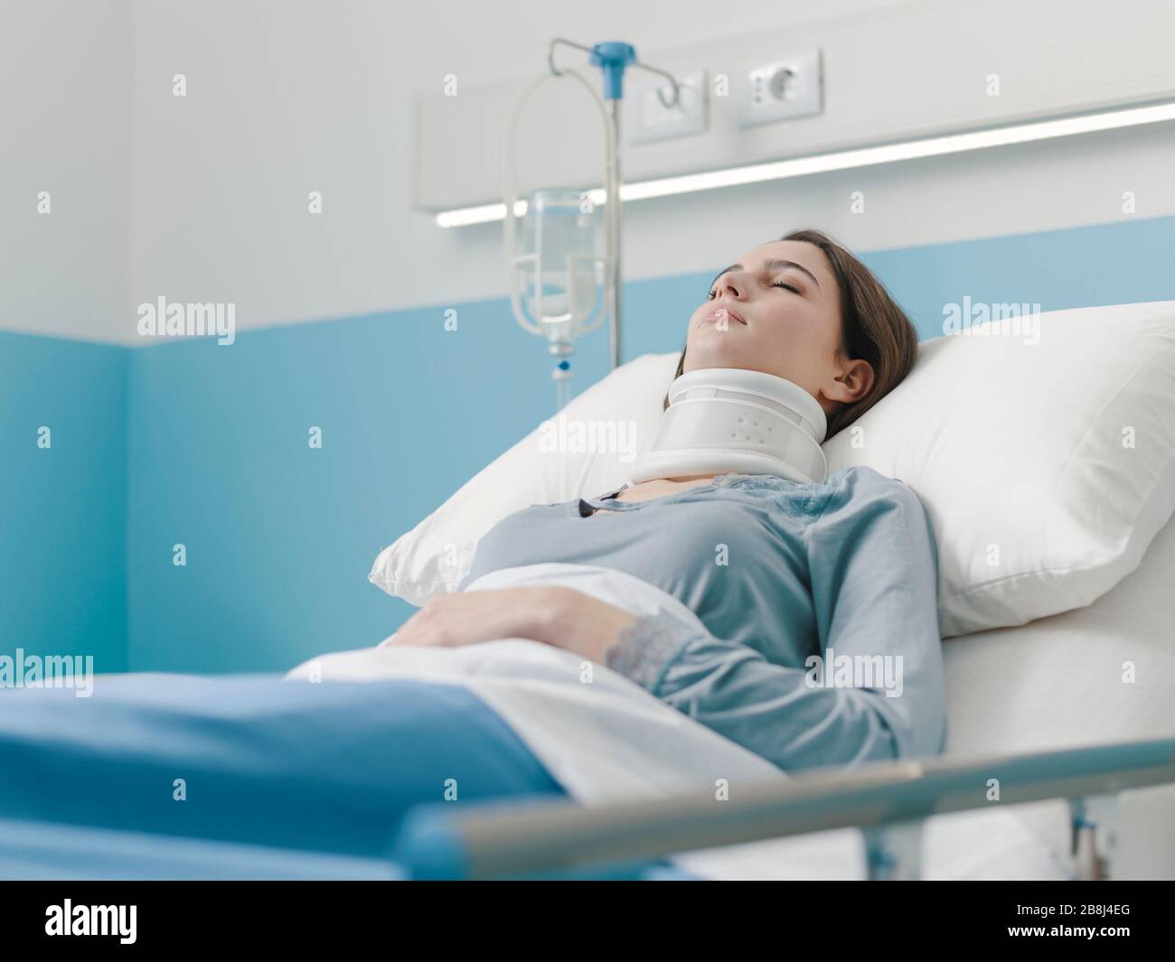 Young woman lying in a hospital bed with IV drip and a cervical collar