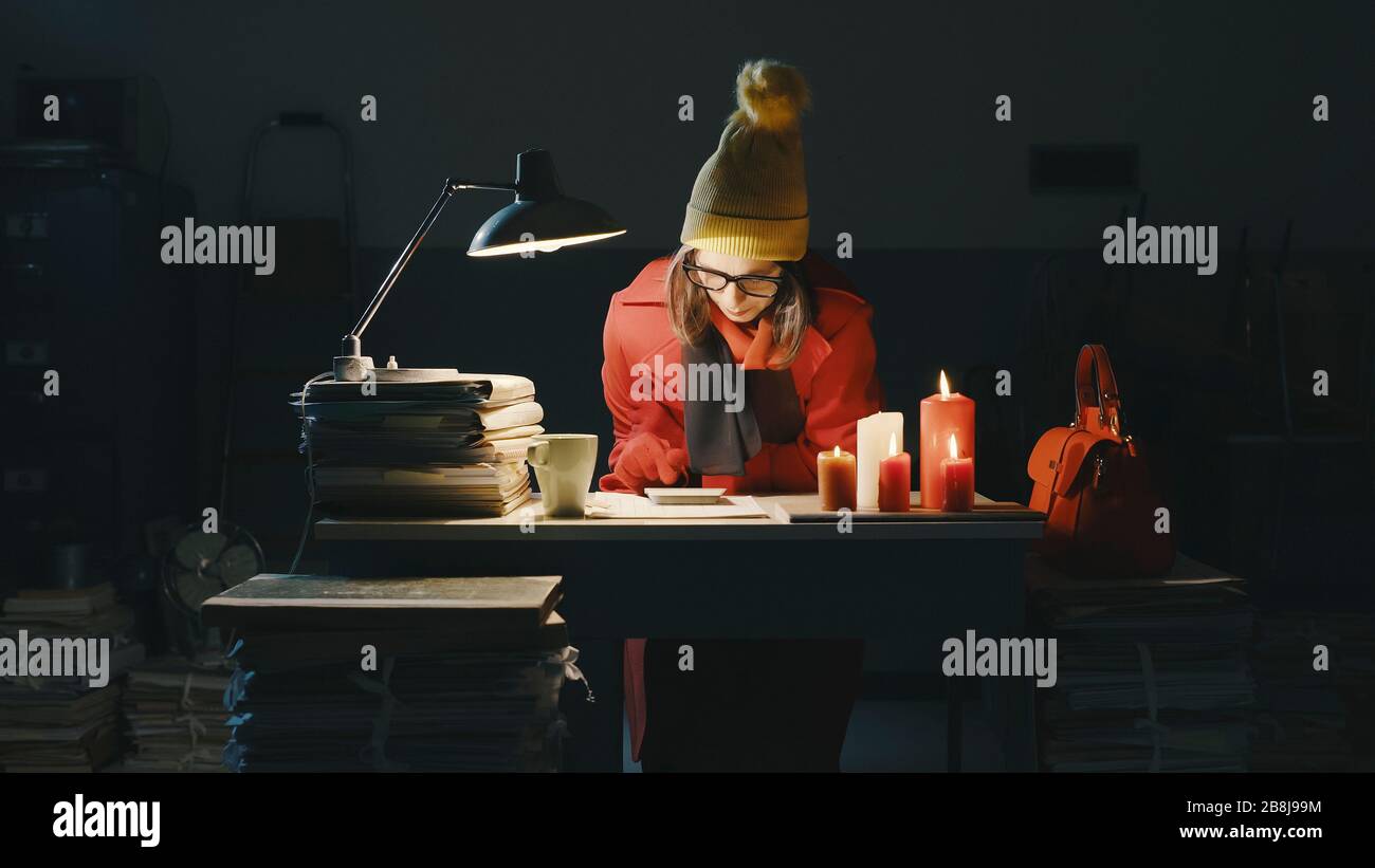 Woman working late at night in the office and freezing, she is warming up  with candles, working overtime and deadlines concept Stock Photo - Alamy