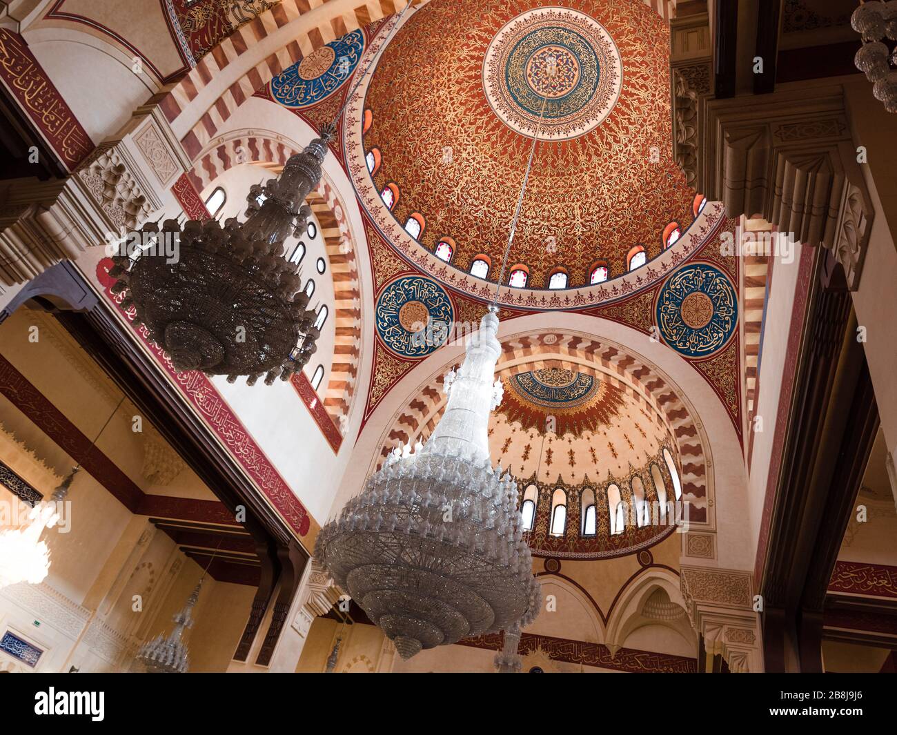 BEIRUT, LEBANON - 01 Apr 2017: The decorated mosque cupola from inside, with Arabic script paintings and hanging glass chandeliers in Al-Amine mosque, Stock Photo