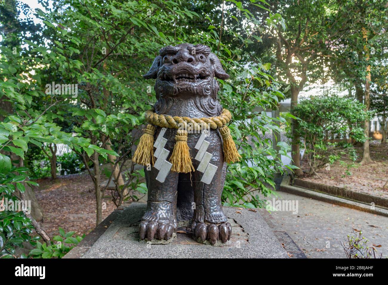 Lion-dog, or komainu, at Saiichi shinto Shrine, Kanazawa, Japan.These traditional statues ward off evil spirits. Around it is the sacred shimenawa rop Stock Photo