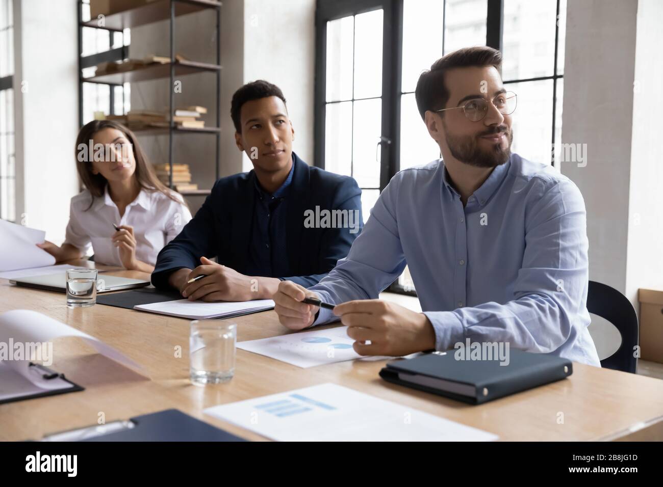 Multiracial businesspeople listen to office presentation or training Stock Photo