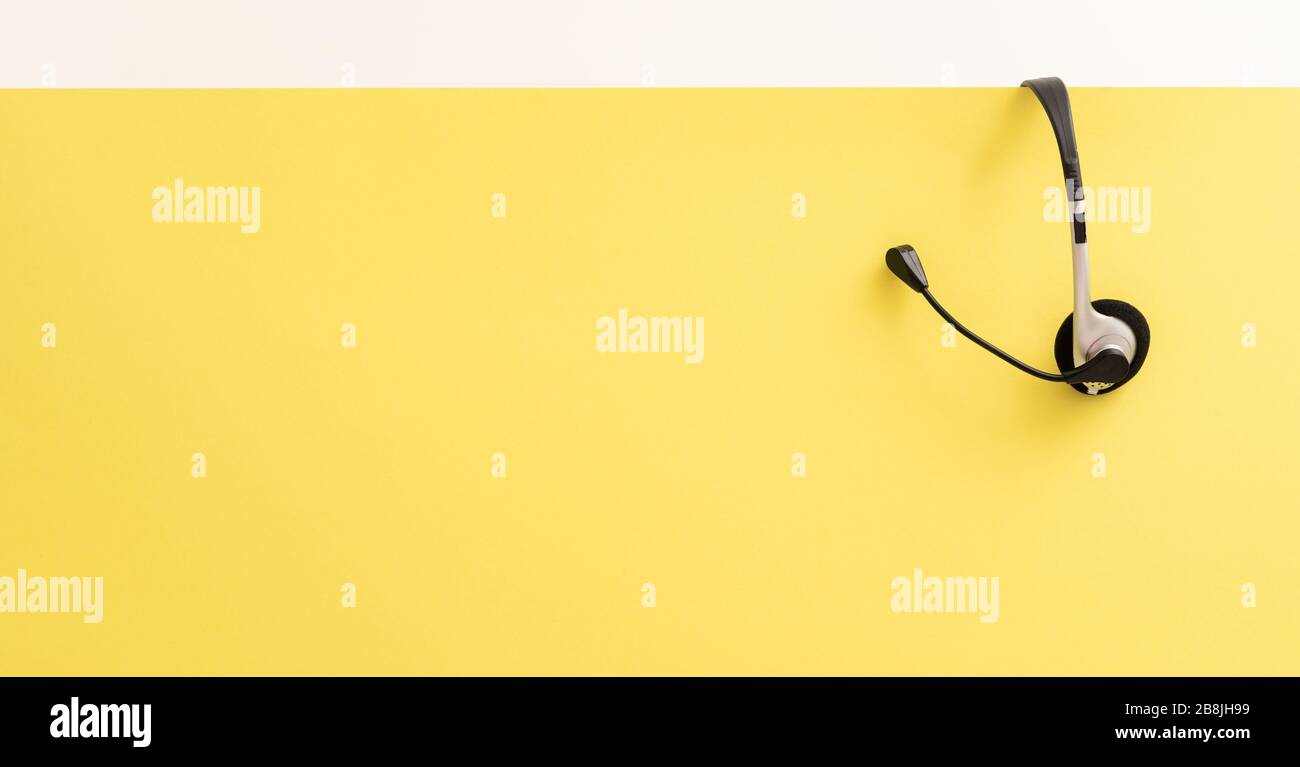 Communication support, call center and customer service help desk. VOIP headset on yellow wall background. Stock Photo