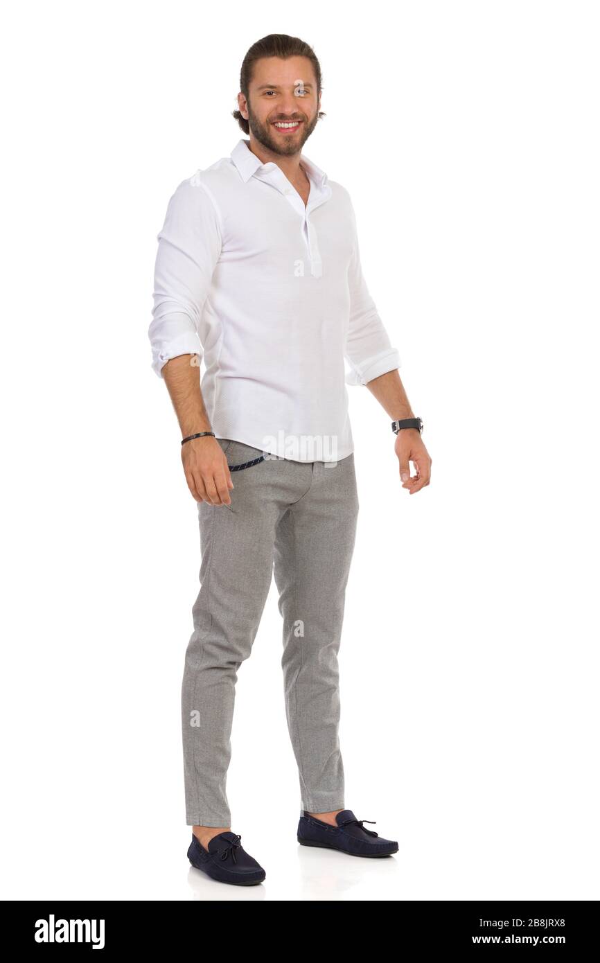 young handsome man in white shirt gray pants and moccasins is standing and looking at camera full length studio shot isolated on white 2B8JRX8