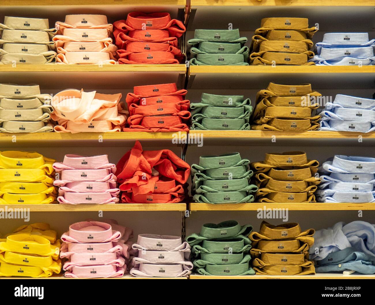 Shirts arranged by colour on display in a store. Stock Photo