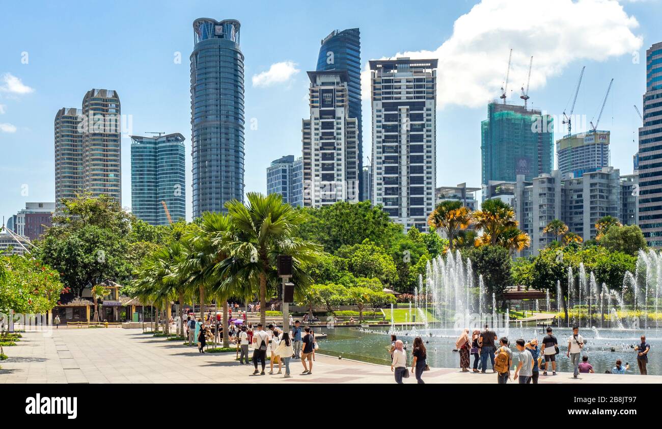 Office and residential high rise towers and fountains in Symphony Lake and tourists enjoying a day at KLCC Park Kuala Lumpur Malaysia. Stock Photo